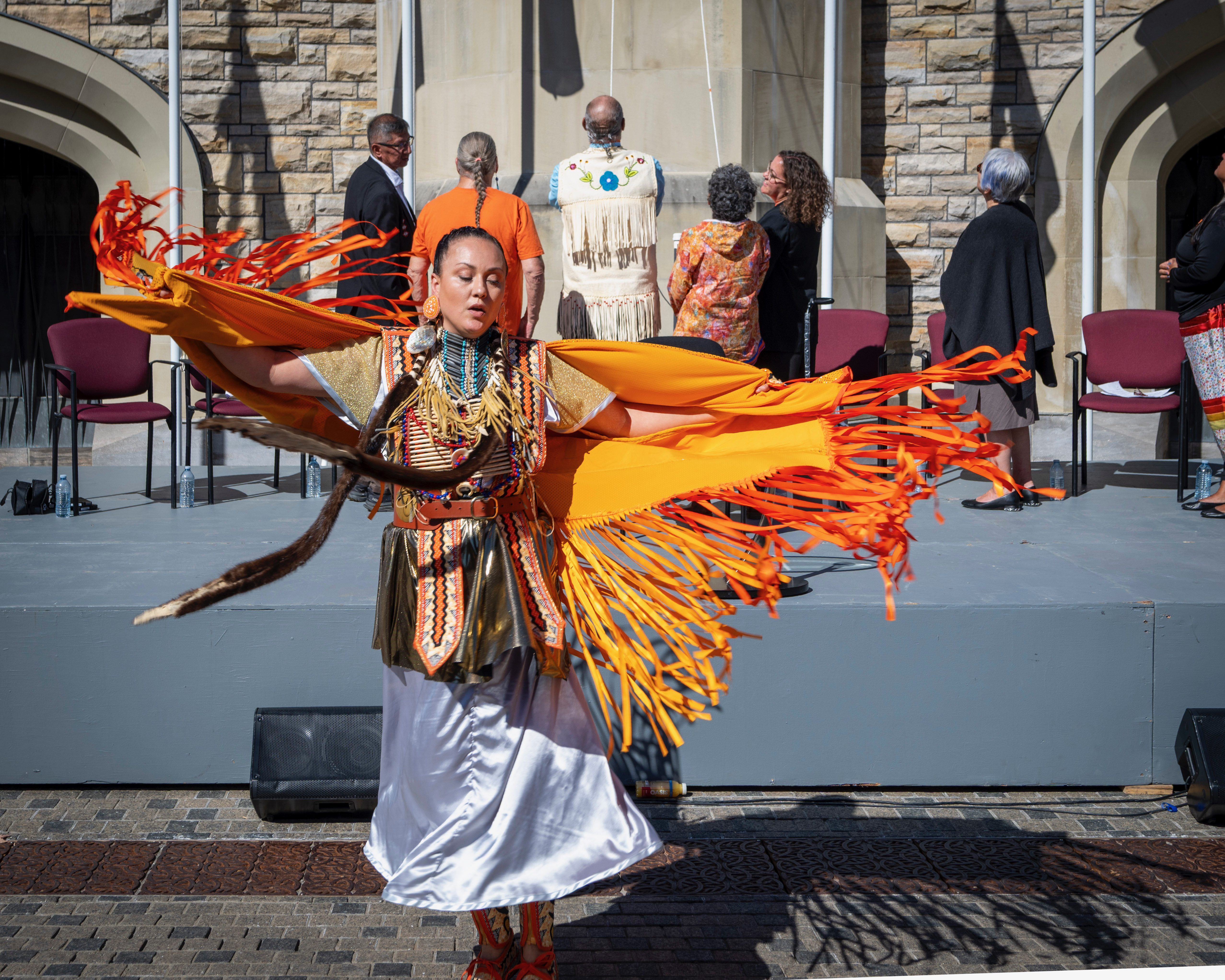 An artist performing a dance while people in the background raise a flag.