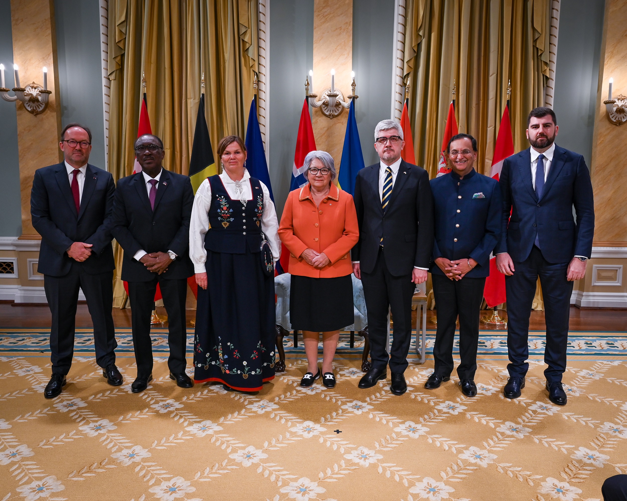 Governor General Simon and six new heads of mission, with the flags of each country behind them.