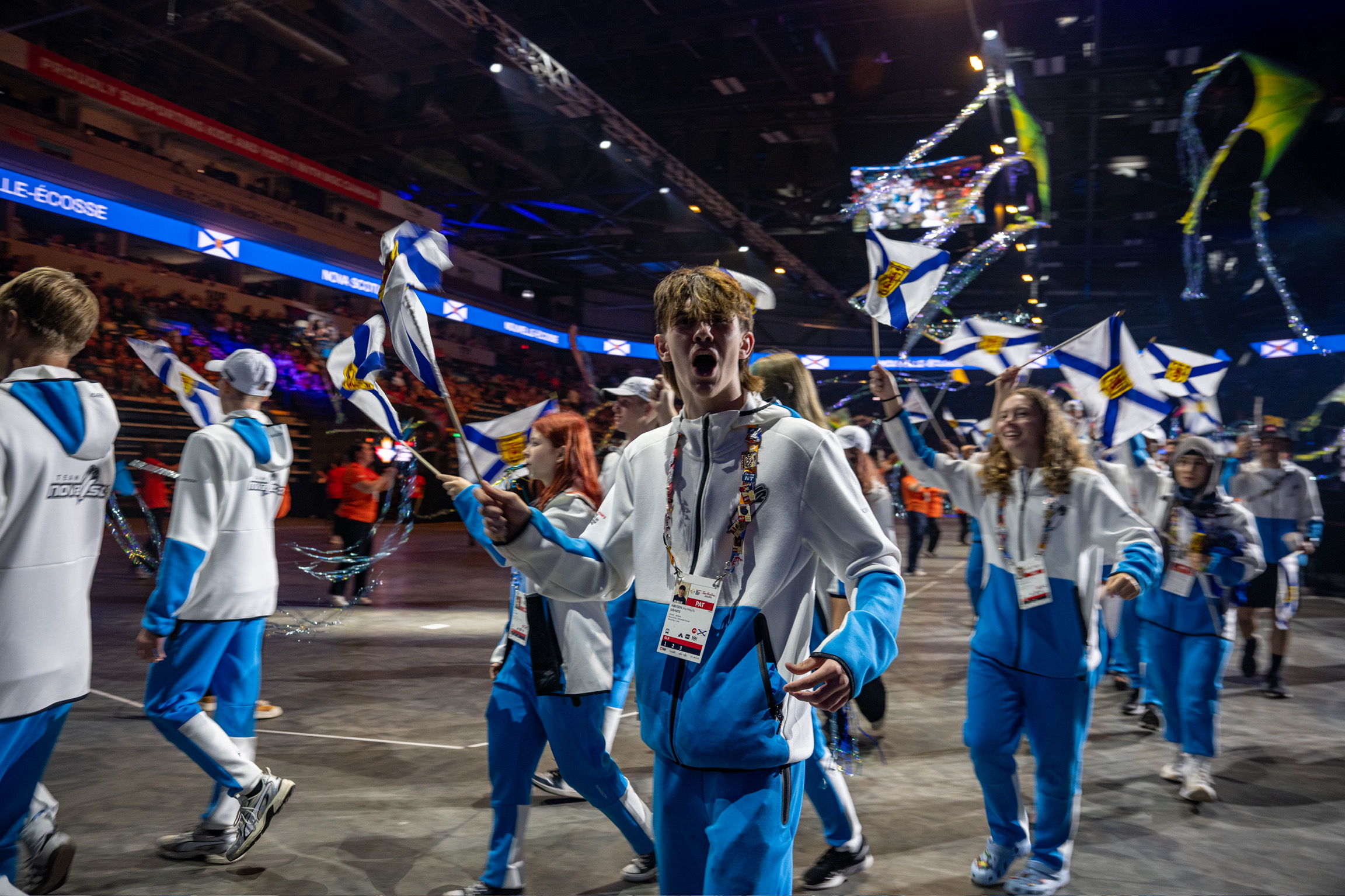 Teams walking in a parade in a large stadium.