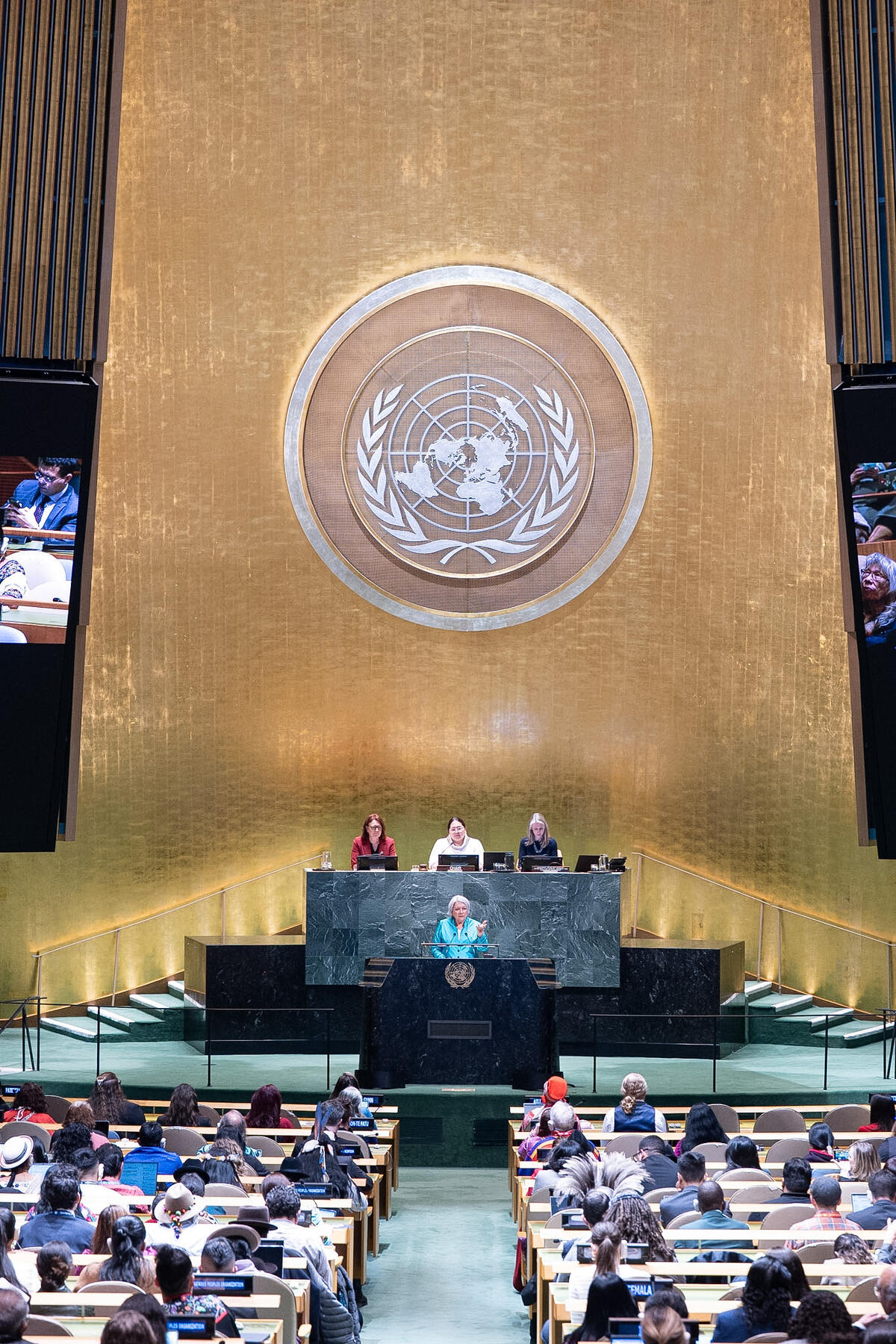 Governor General Mary Simon standing at a podium in a UN conference room. Three people are seated at a large desk behind her.