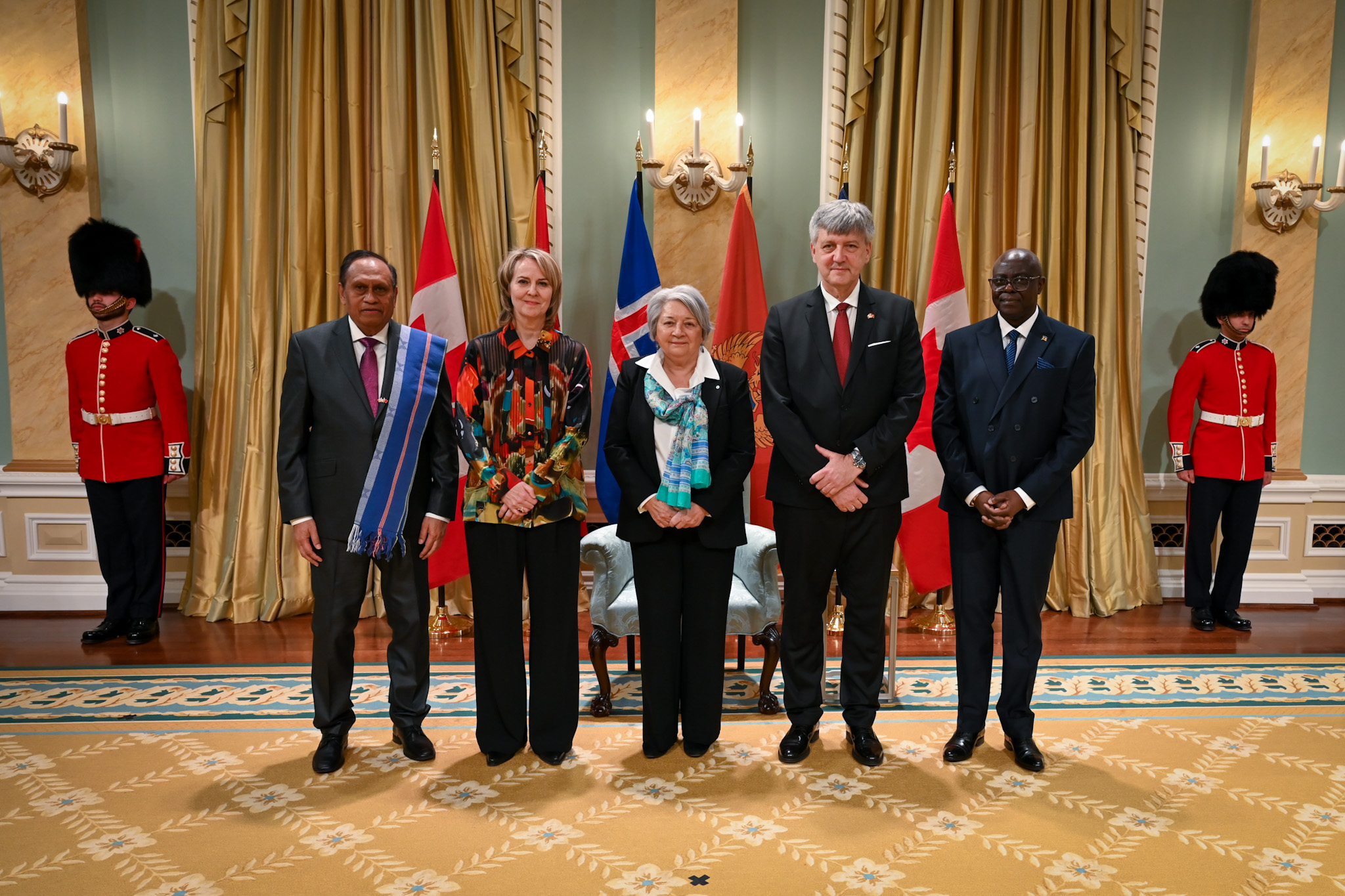 Governor General Simon and four heads of mission, with the flags of each country behind them. Two Ceremonial Guards are in the back.