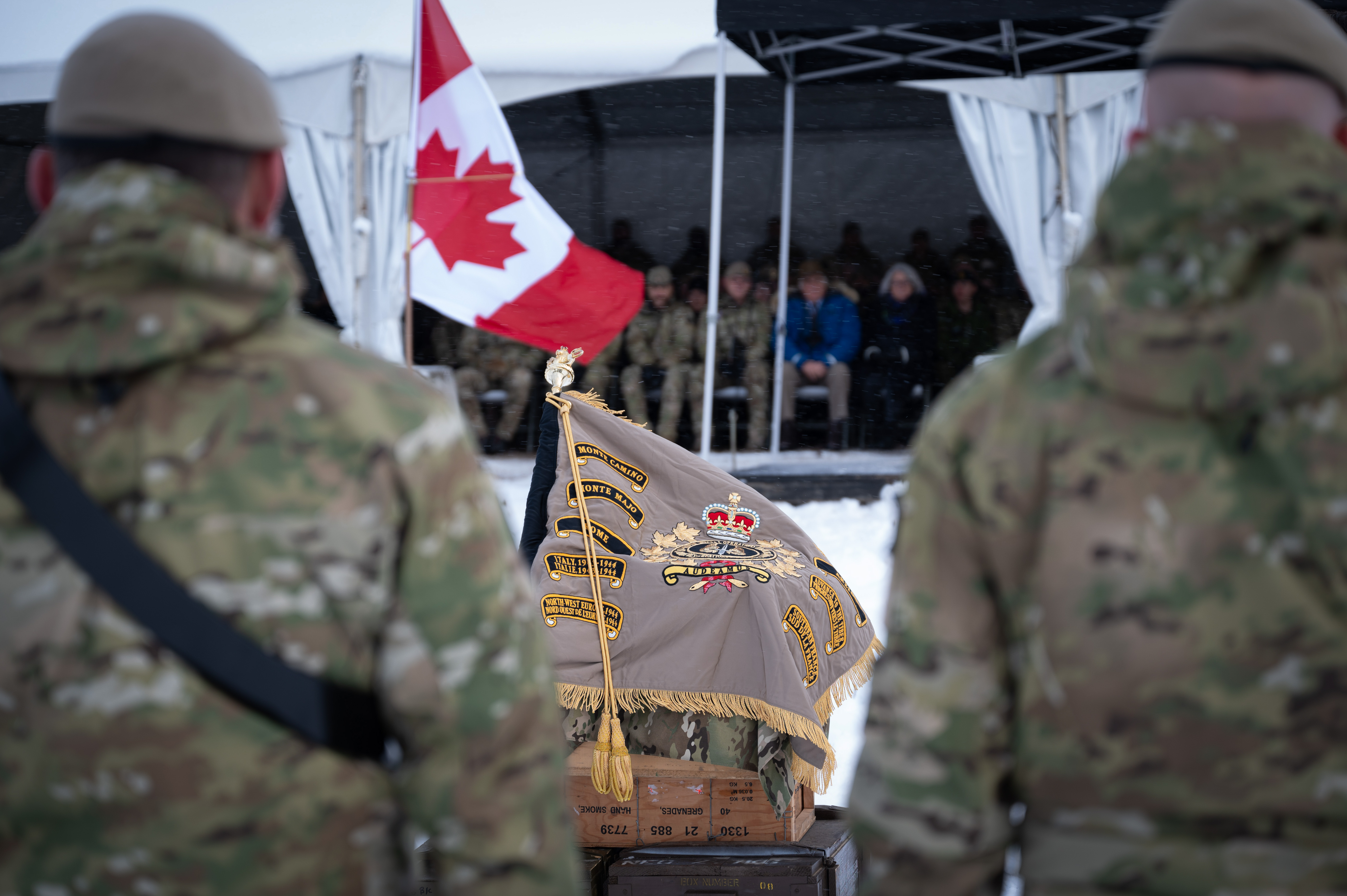 The Canadian Special Operations Regiment's standard, placed on an alter outdoors with two members of the Canadian Armed Forces in soft focus at the front.