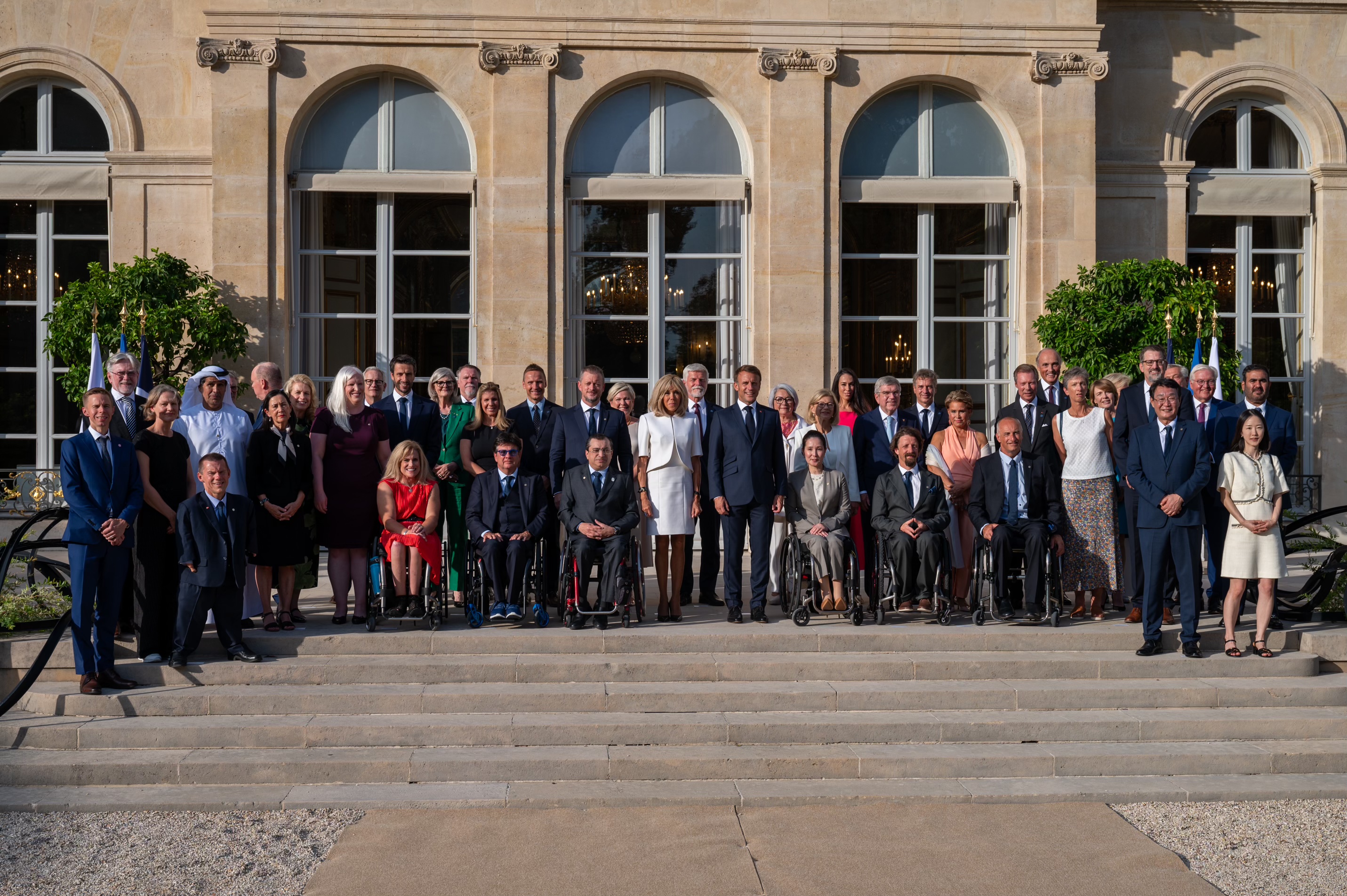 La gouverneure générale du Canada Mary Simon, le Président Emmanuel Macron et sa femme Brigitte Macron se tiennent parmi un grand groupe de personnes. 
