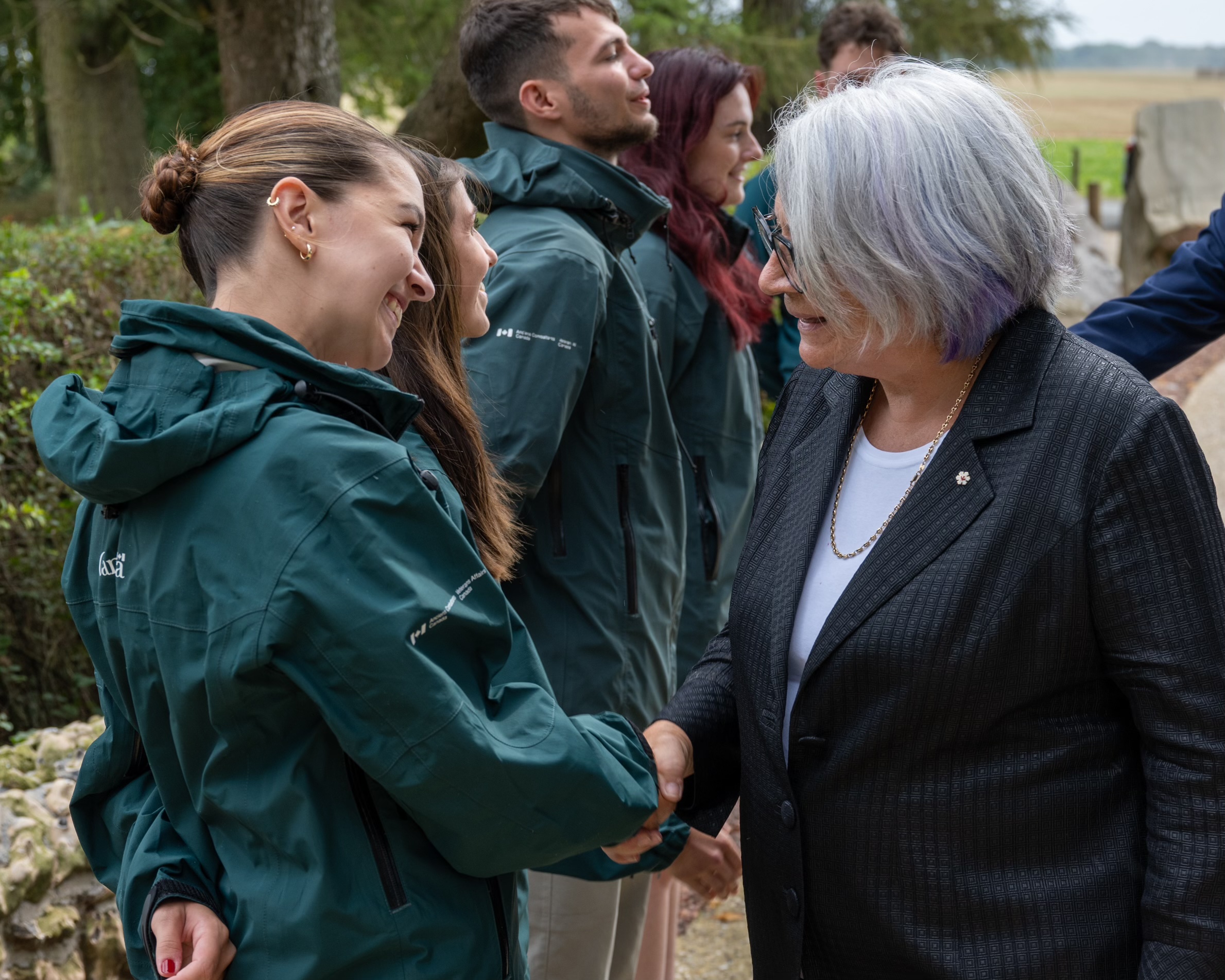 Un groupe de personnes en uniformes verts se tient en ligne, serrant la main de la gouverneure générale du Canada, Mary Simon.