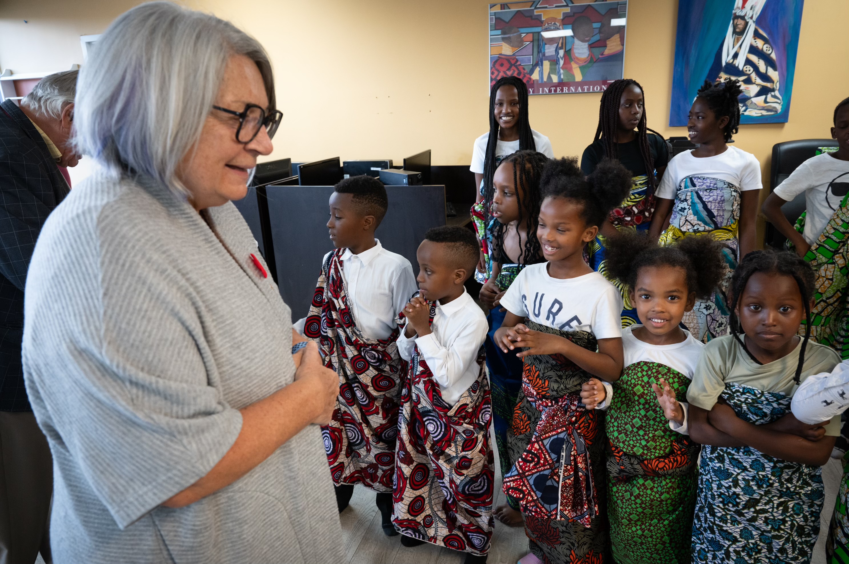 Governor General Mary Simon stands before a group of children. They are all smiling.