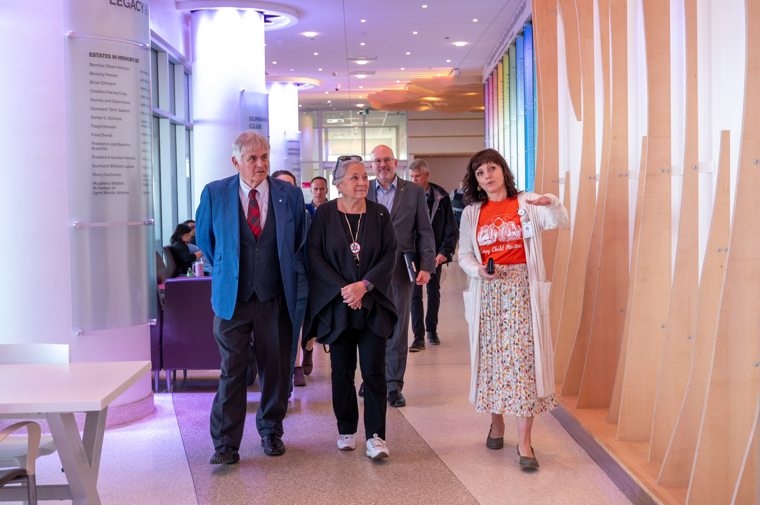 La gouverneure générale Simon et M. Whit Fraser marchant avec un groupe de personnes dans un couloir d'hôpital.