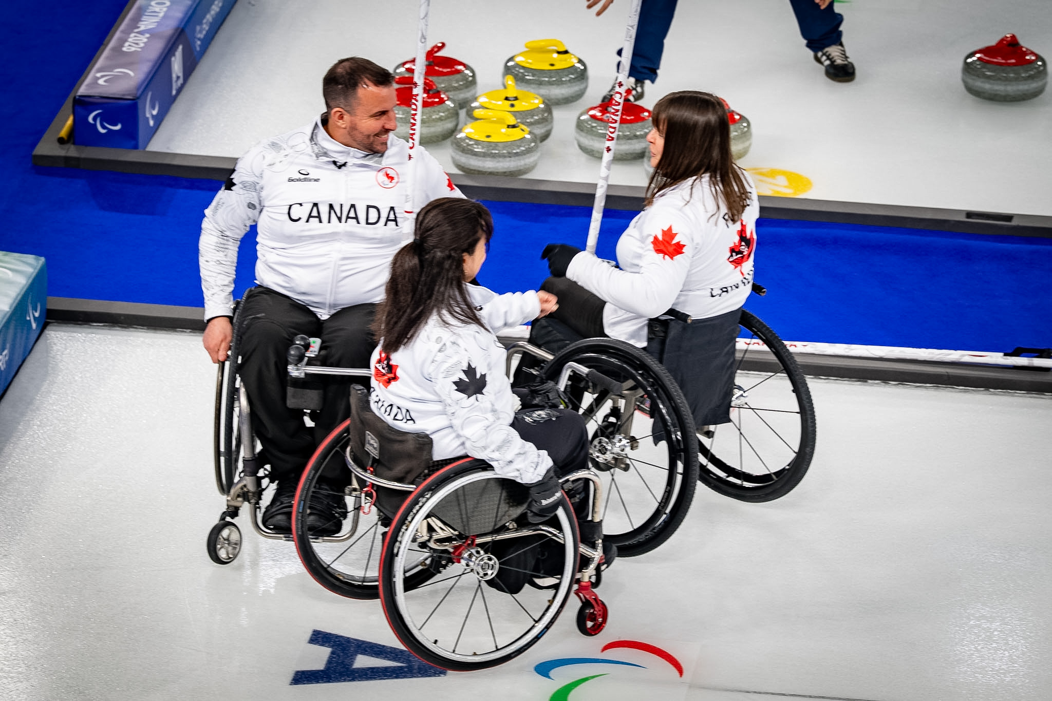 Three members of a curling team in wheel chairs.