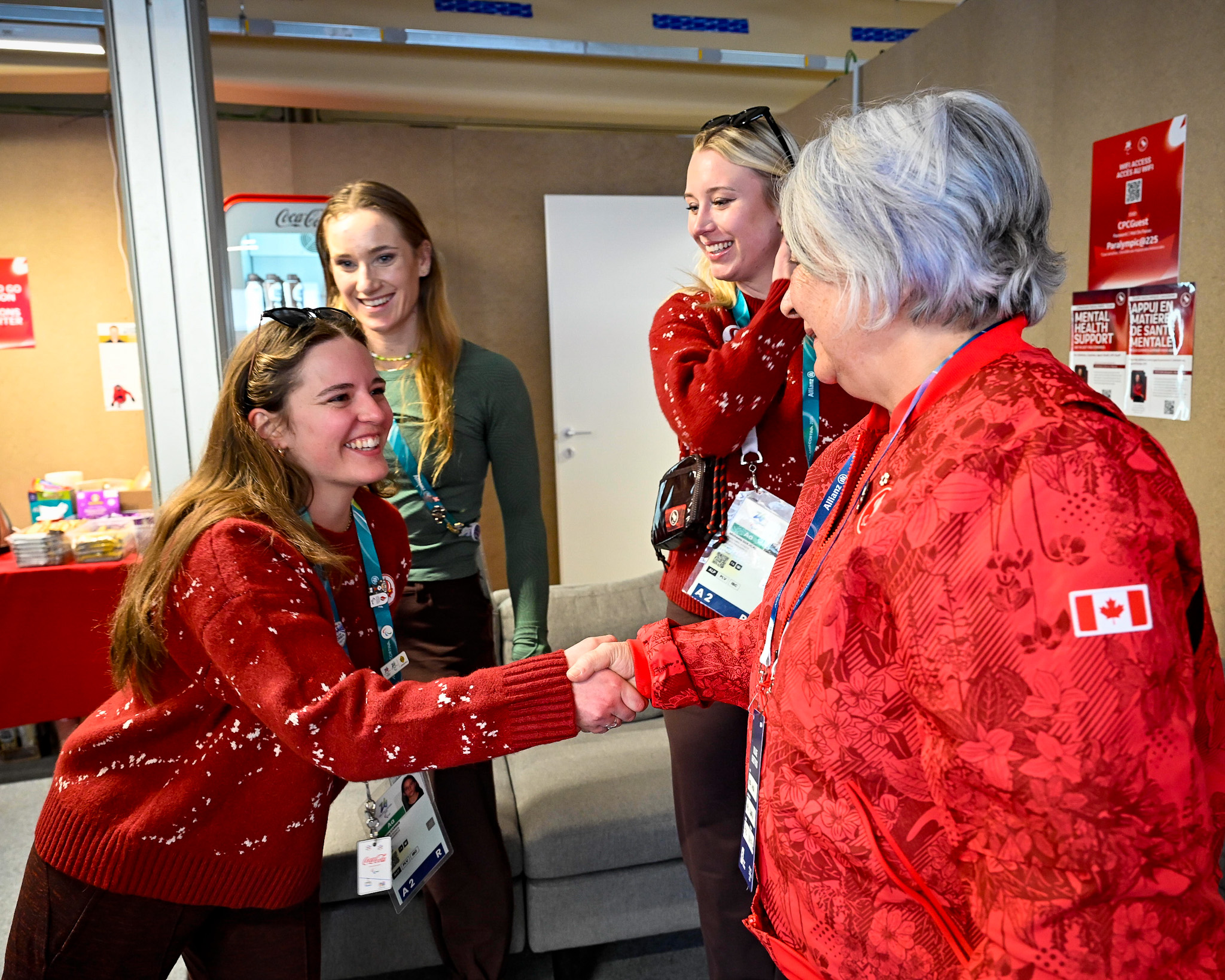 Governor General Mary Simon standing with a group of Paralympic athletes. She is shaking hands with one of them.