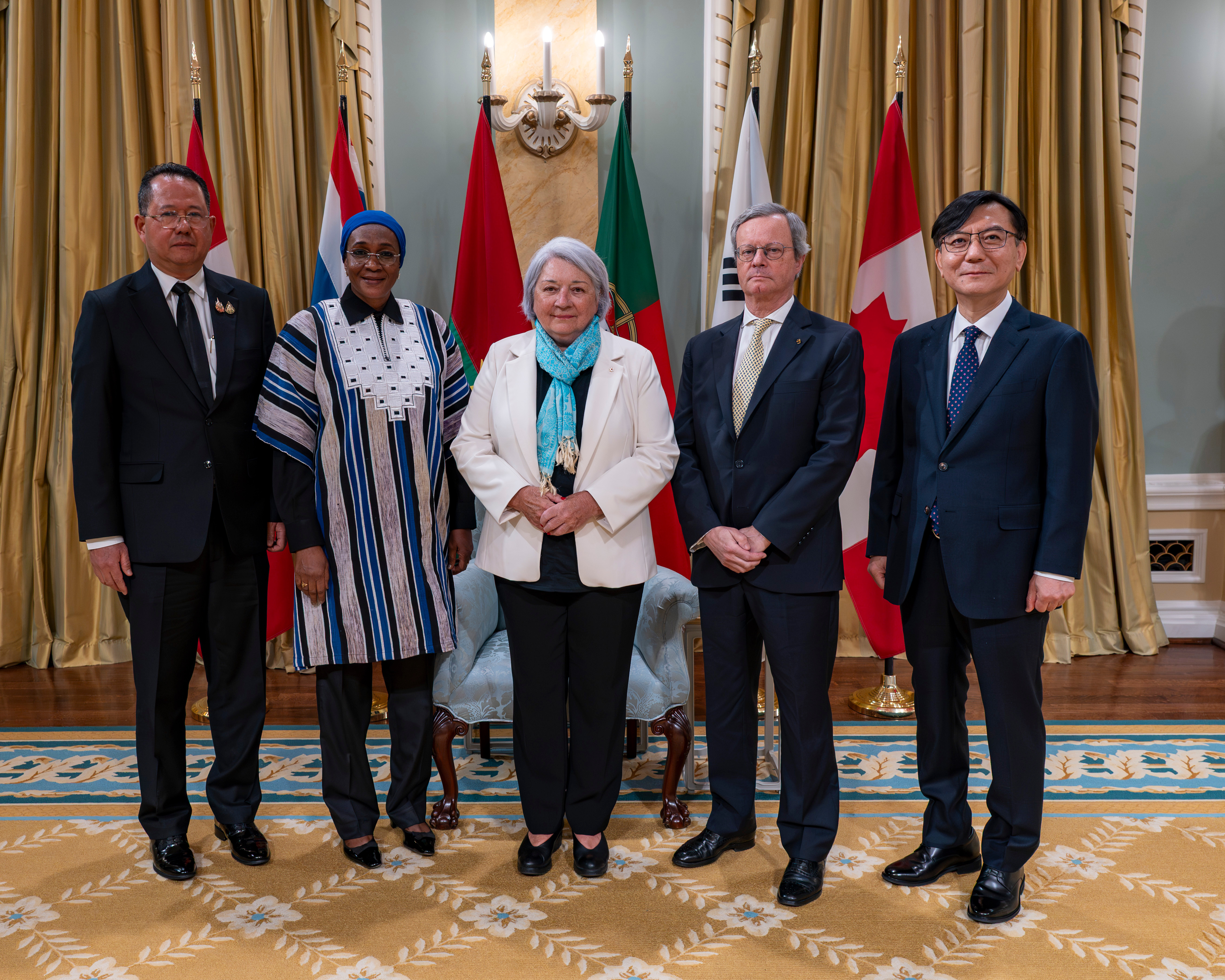 Governor General Simon standing with four new heads of mission, with the flags of each country behind them, with Canada flags on either end.