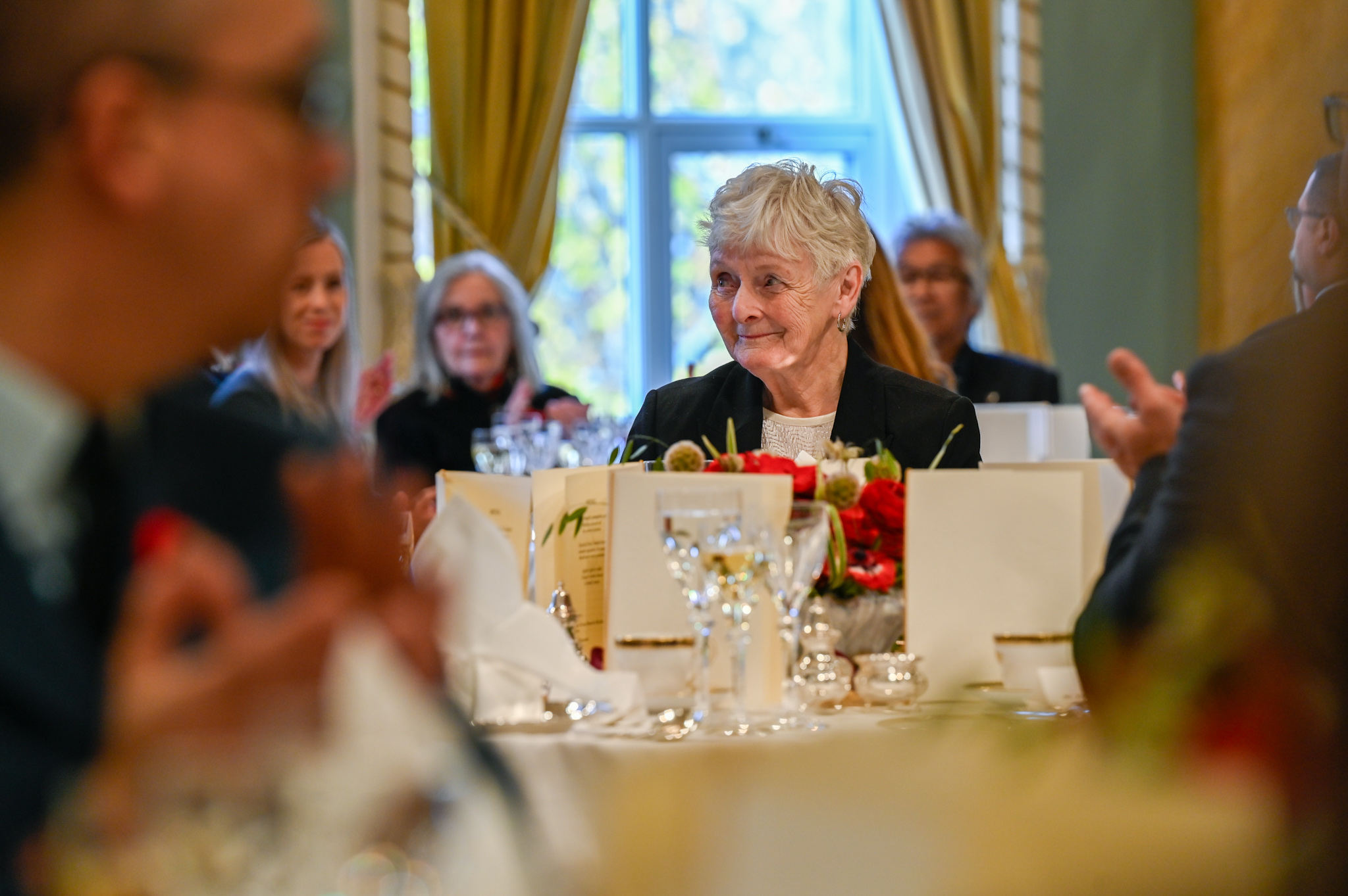 A woman sitting at an elegant dining table in a ballroom.