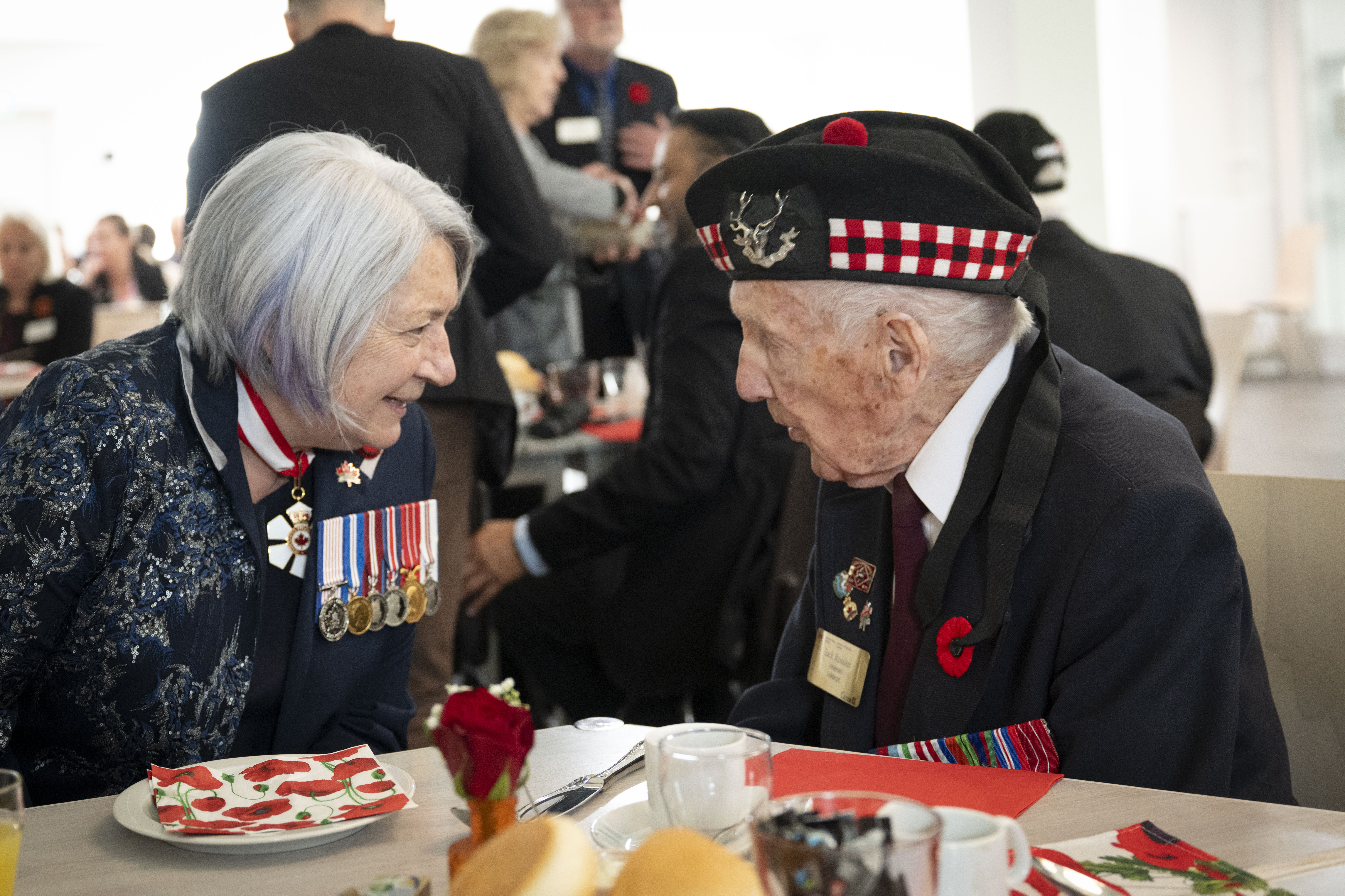 La gouverneure générale Mary Simon, assise à une table, s'entretenant avec un ancien combattant canadien.