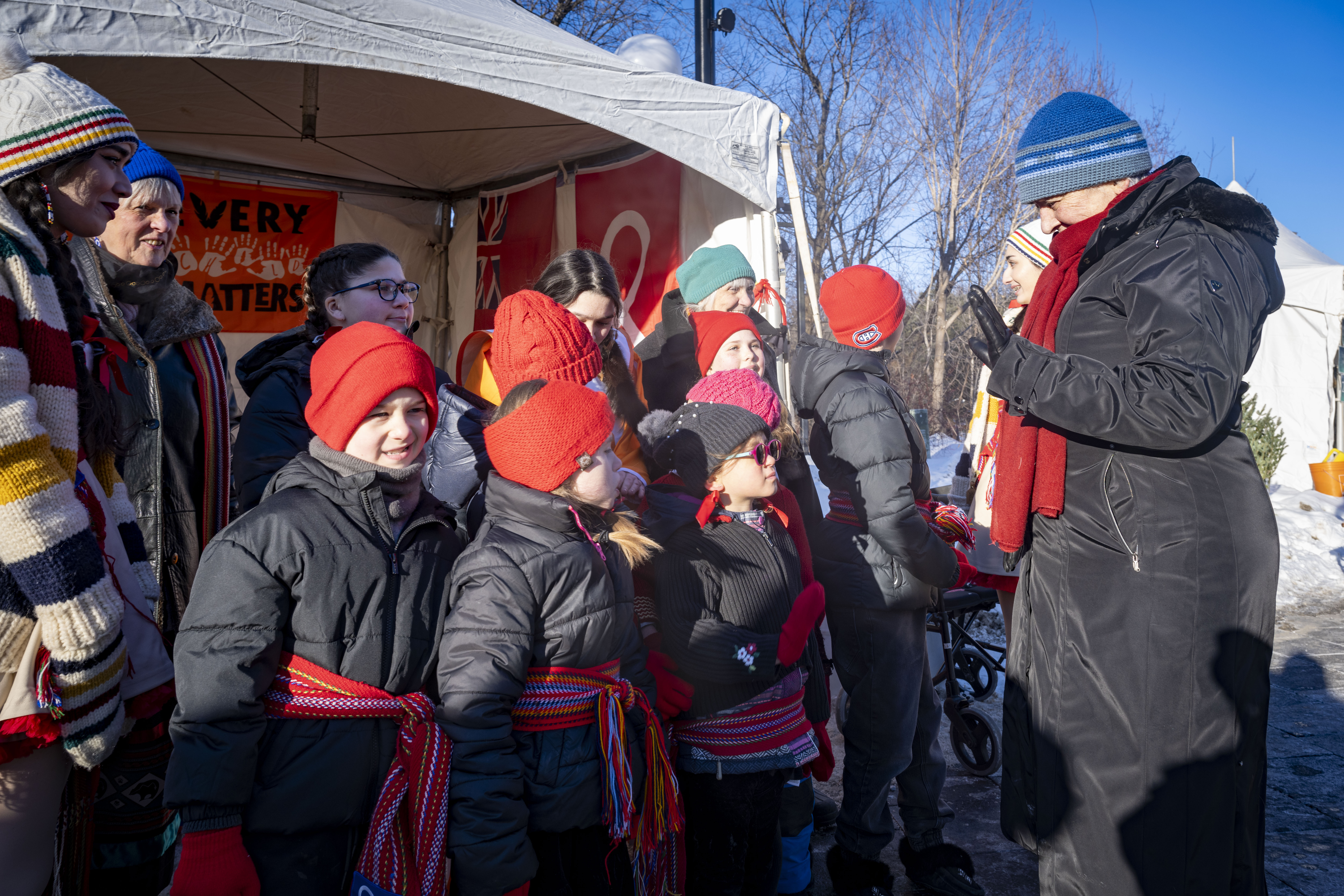 Governor General Mary Simon greeting a group of children. Everyone is dressed warmly for the winter weather.