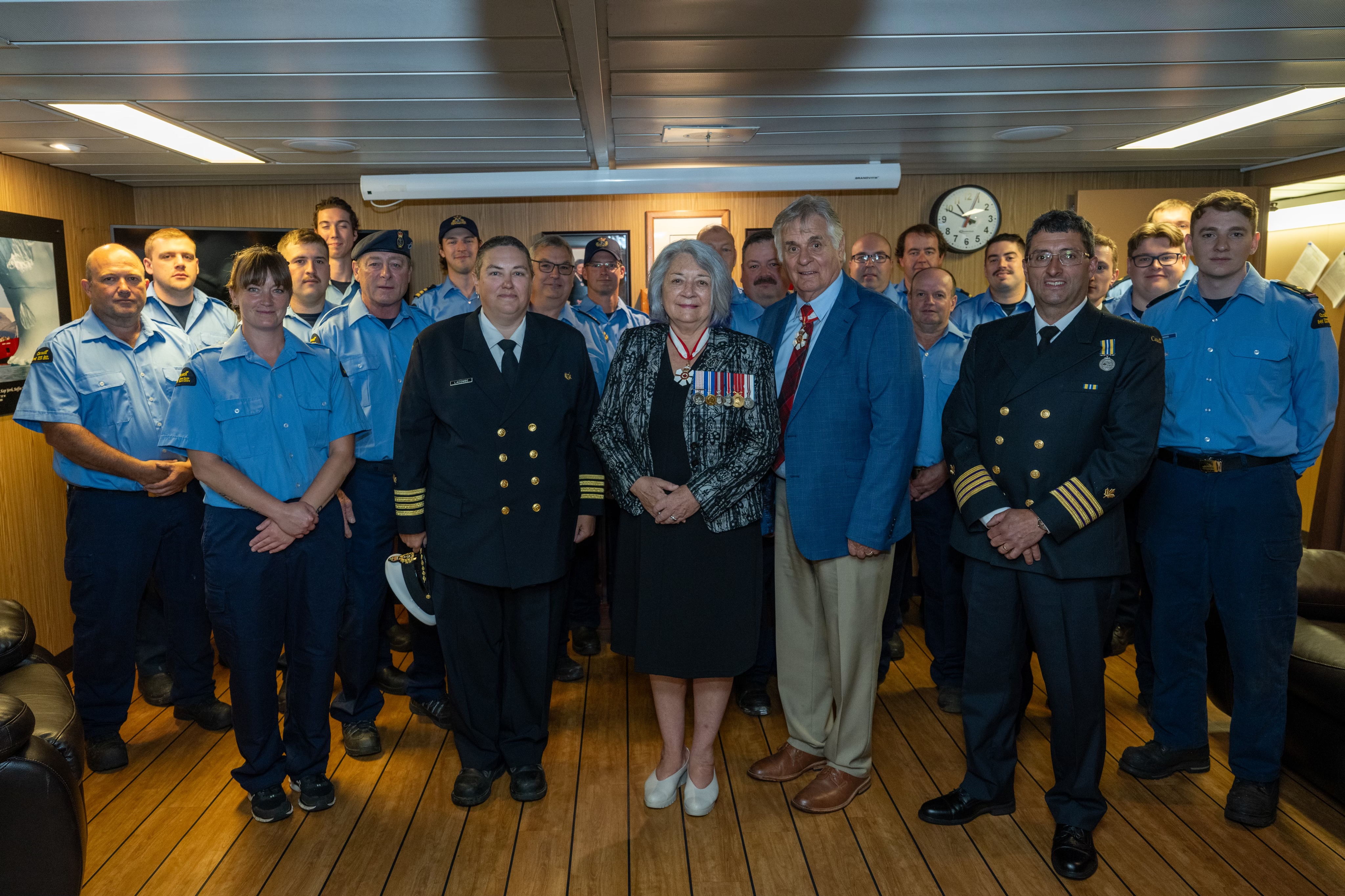 Governor General Simon and Mr. Whit Fraser posing for a photo with a group of people in uniforms.