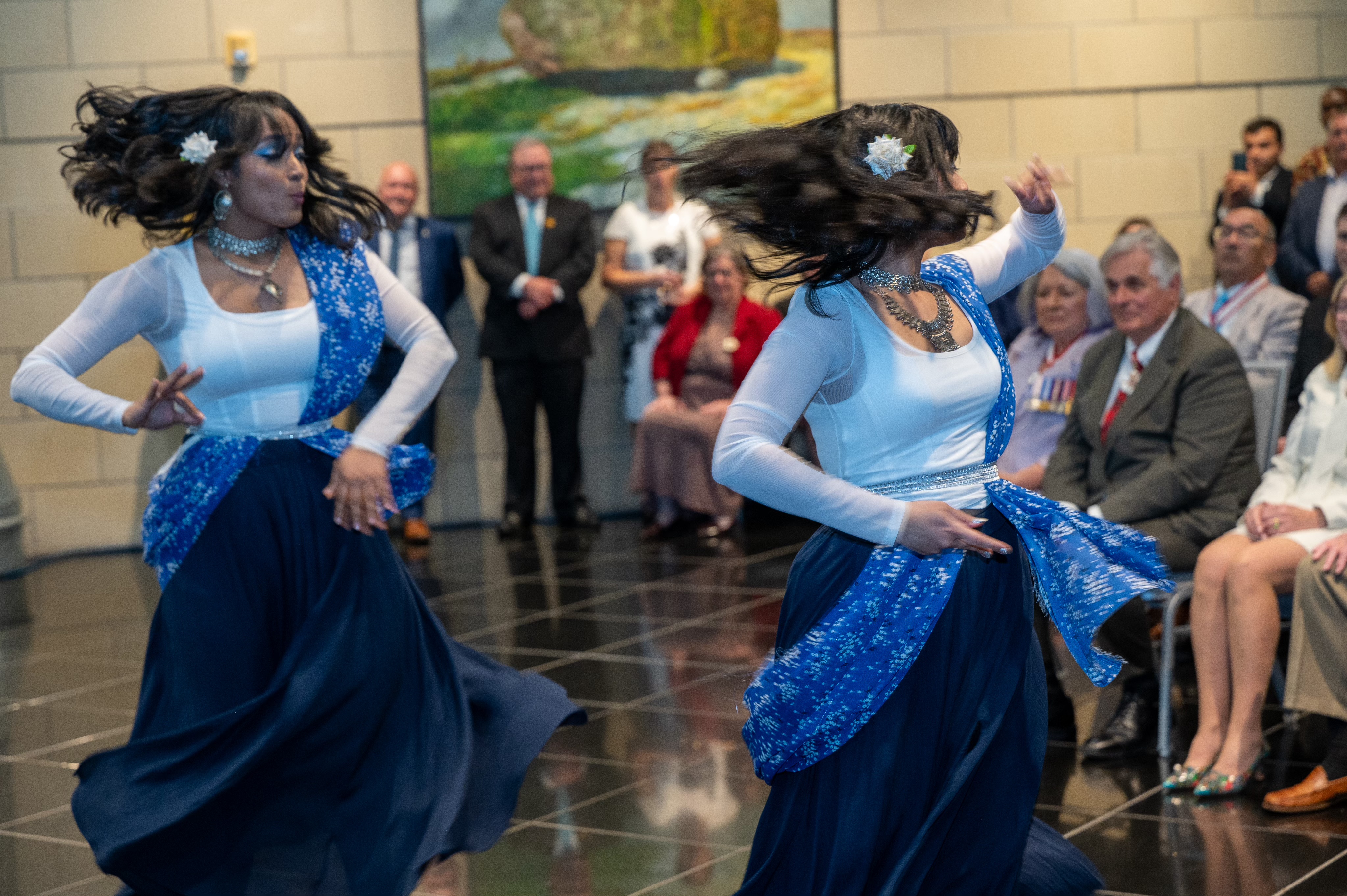 Two dancers perform a dance routine as Governor General Mary Simon and Mr. Whit Fraser watch in the background.