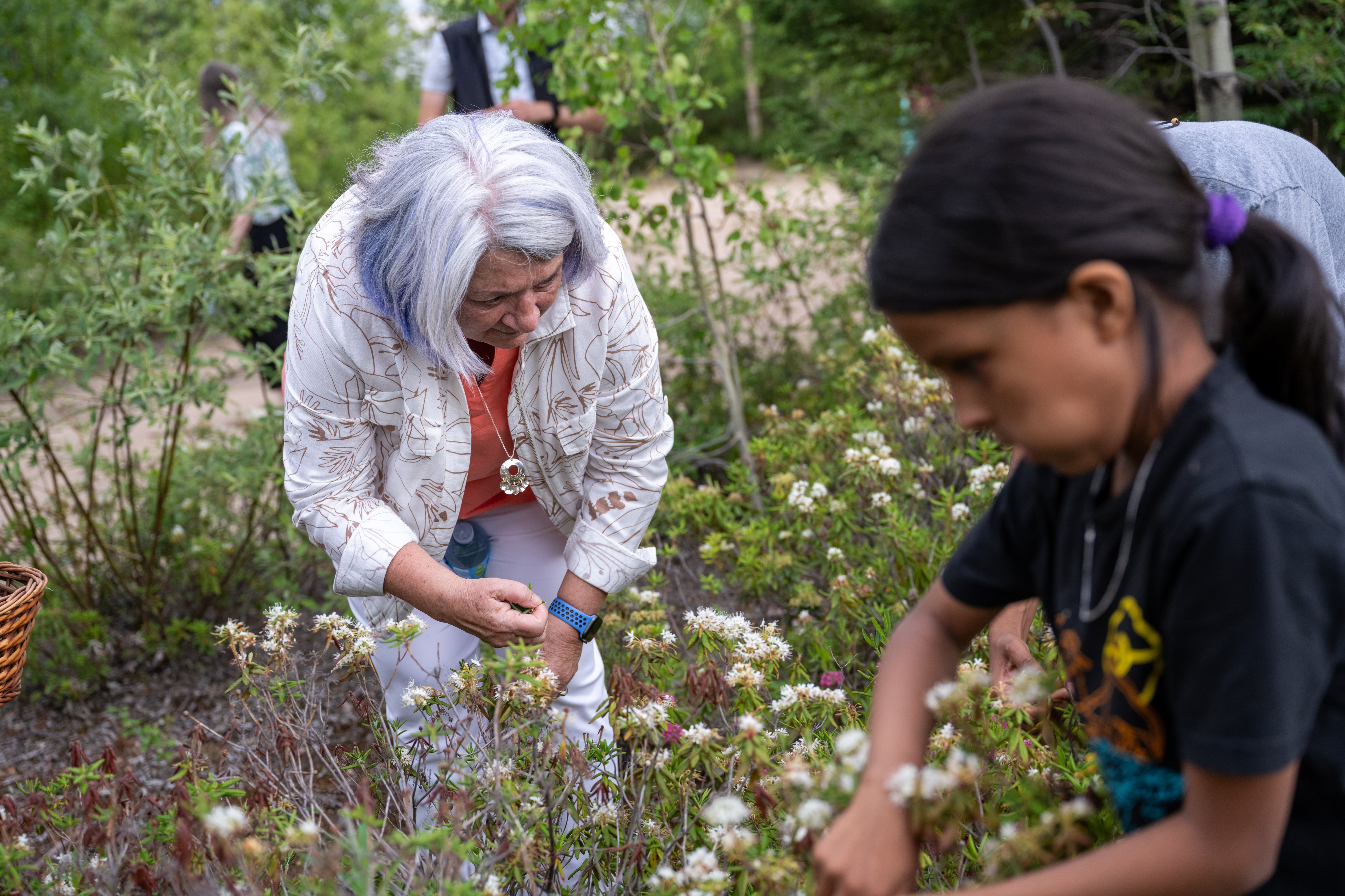 Governor General Mary Simon picks flowers. There is a child in the foreground.
