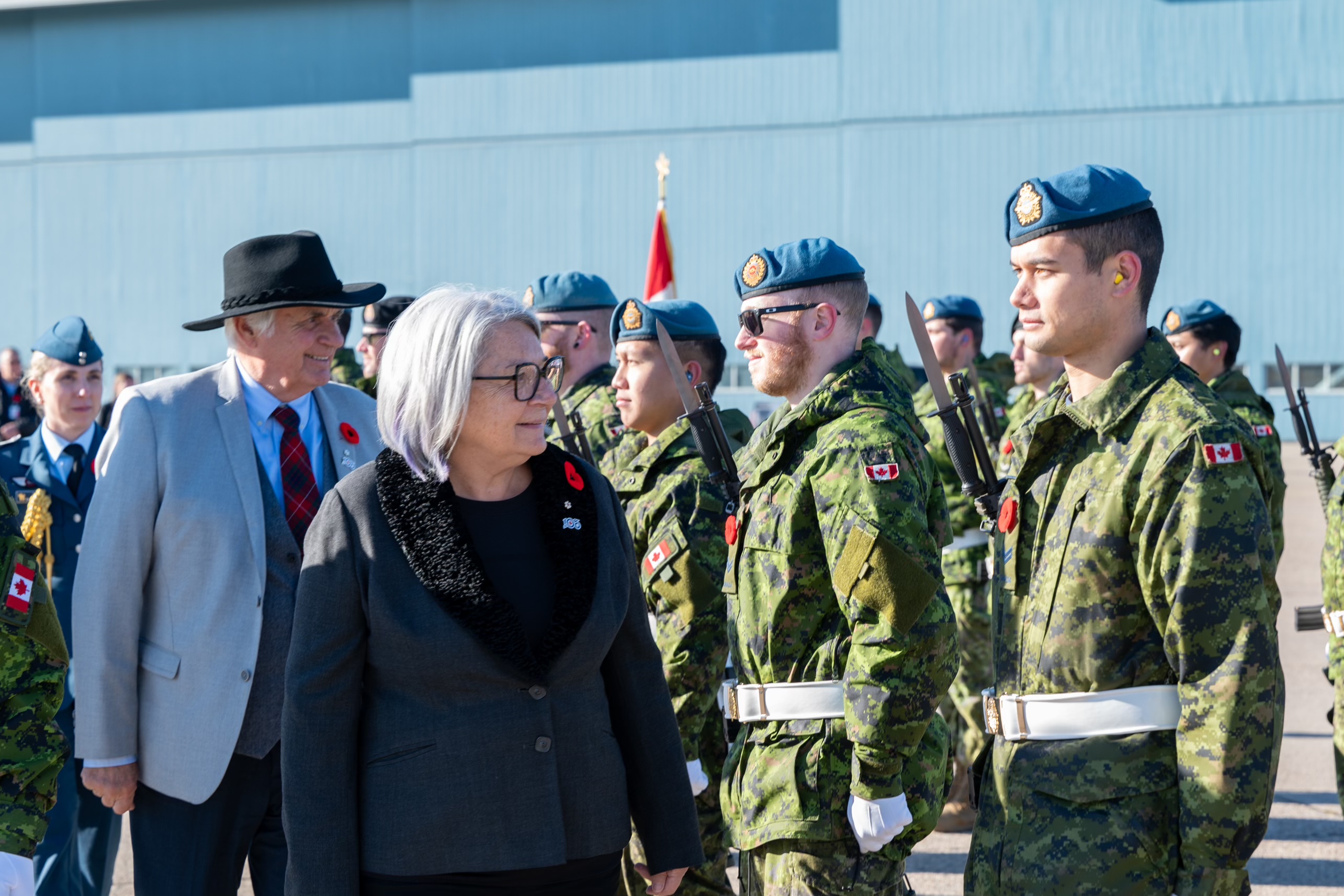 Governor General Mary Simon and Mr. Whit Fraser walk past RCAF members.