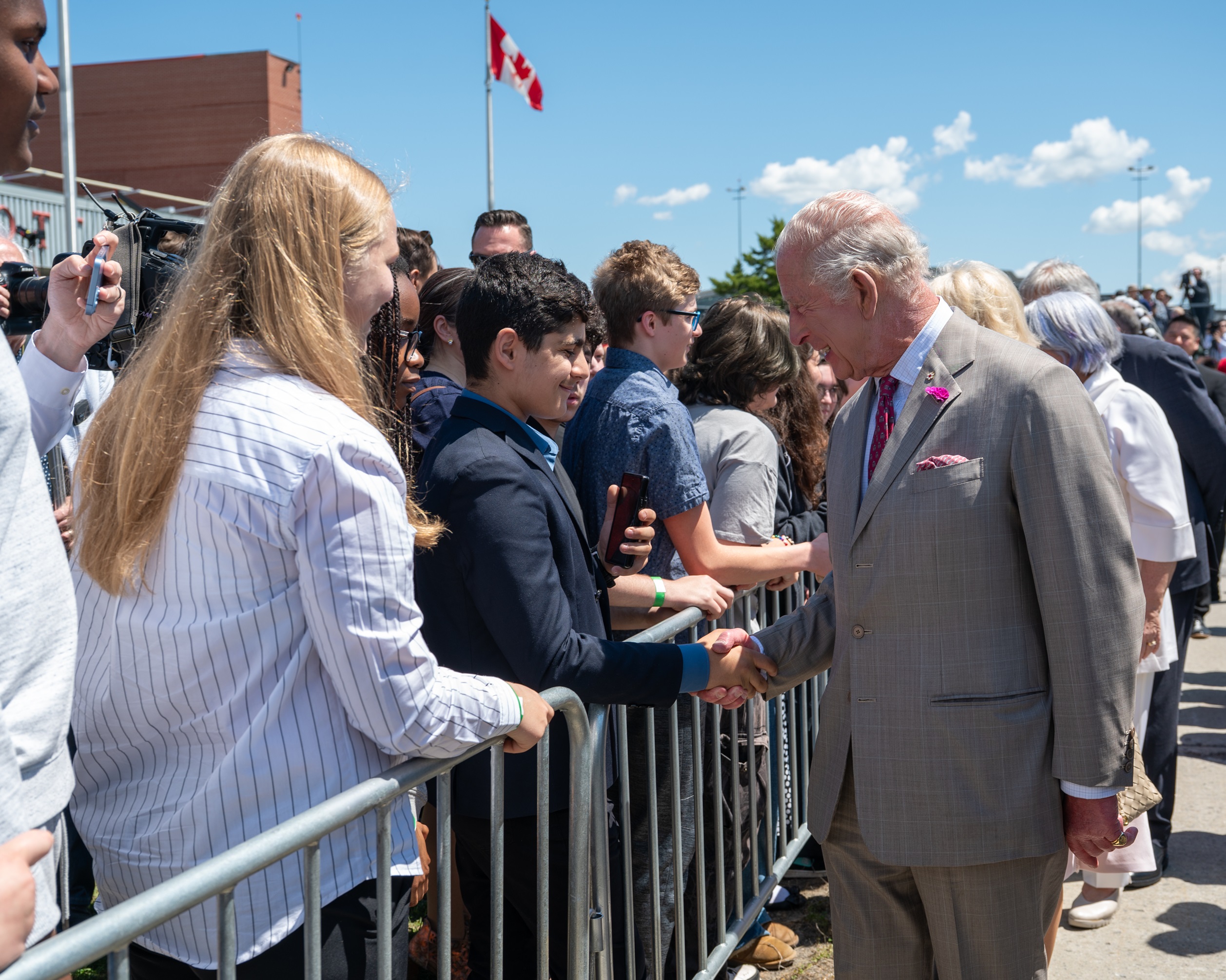 Sa Majesté le Roi Charles III serrant la main d'étudiants à l'extérieur de l'aéroport.