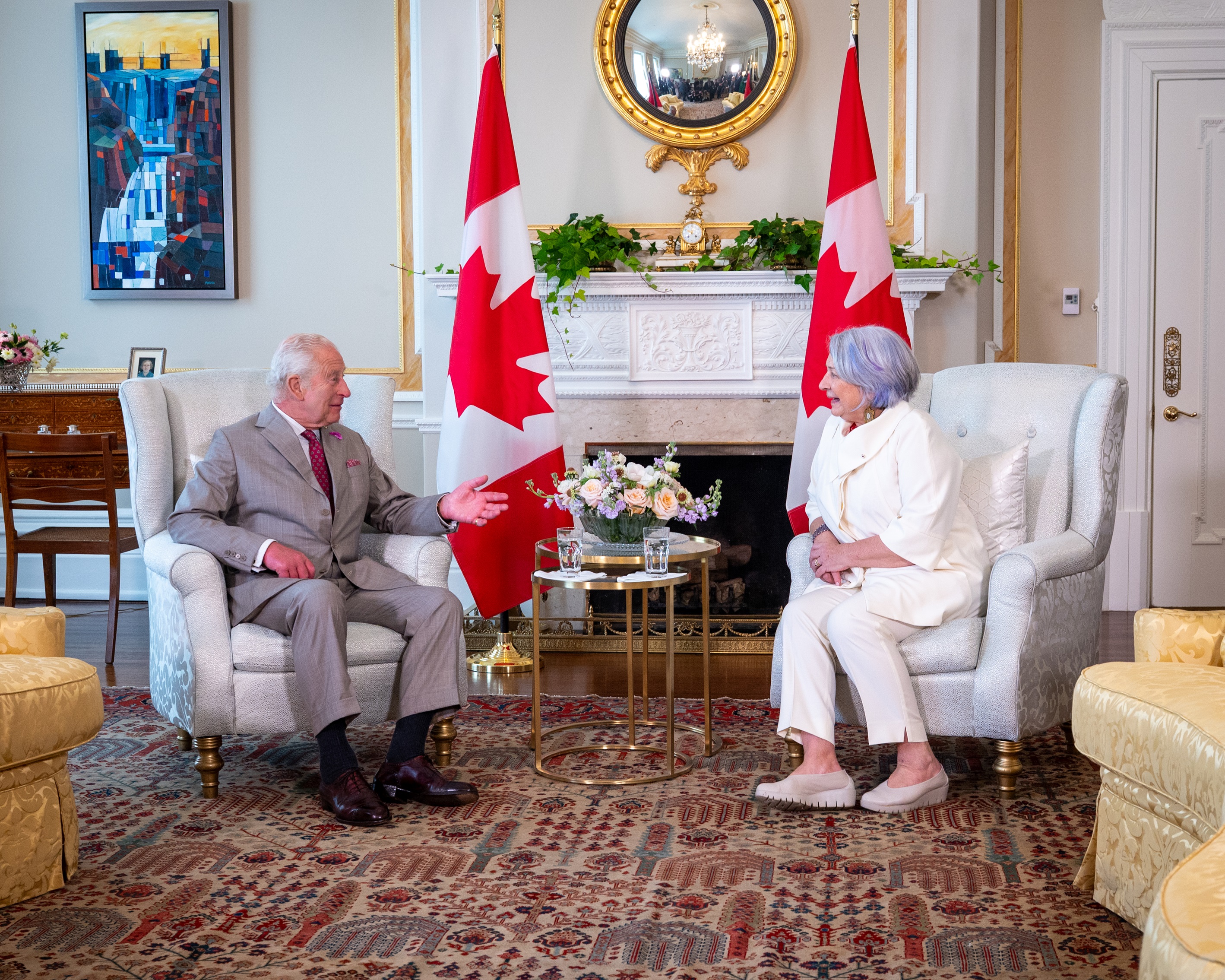 Governor General Simon and King Charles III sitting in chairs. There is a fireplace behind them.
