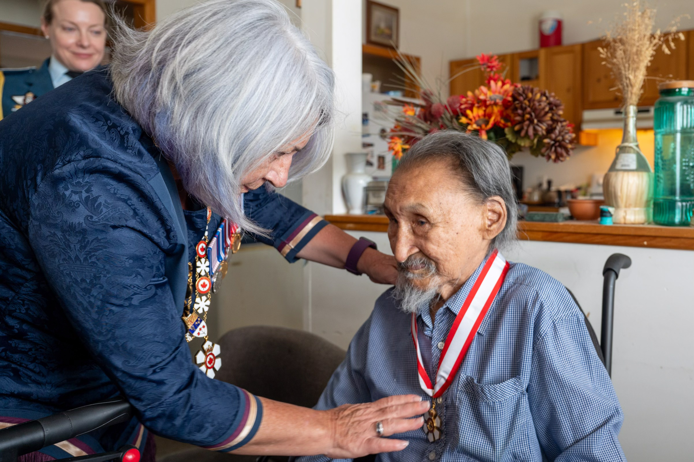 Governor General Mary Simon places the insignia around John Amagoalik's neck.