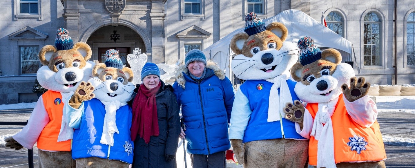 Governor General Mary Simon and Mr. Whit Fraser posing with Winterlude mascots outside of Rideau Hall.
