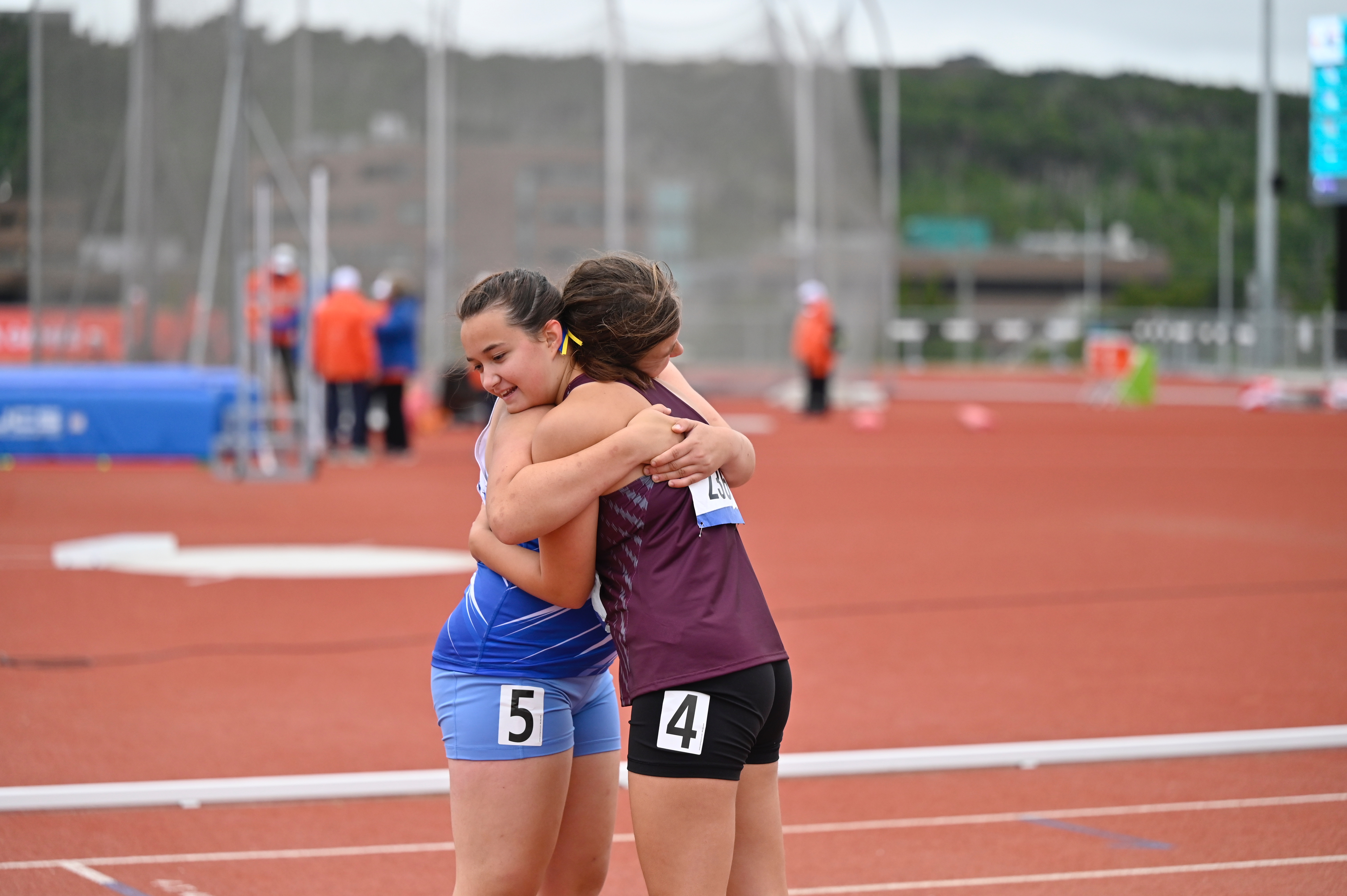 Two athletes hugging each other on a running track.
