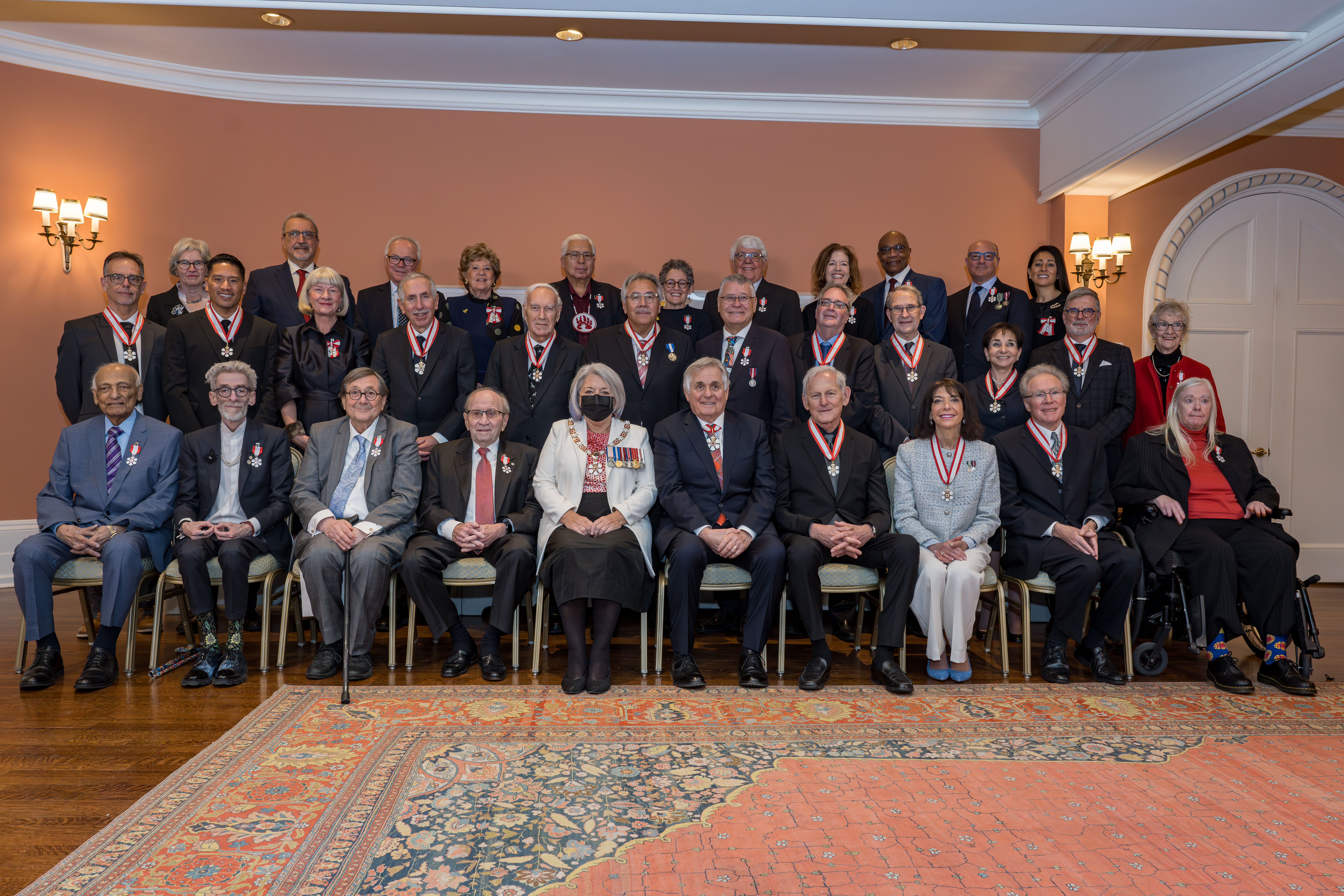 Governor General Mary Simon and Mr. White Fraser sitting in the center of a group photo featuring members of the Order of Canada.