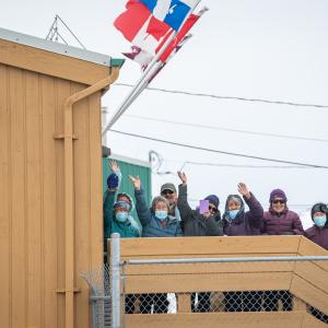 A crowd of people is waving outside the airport.