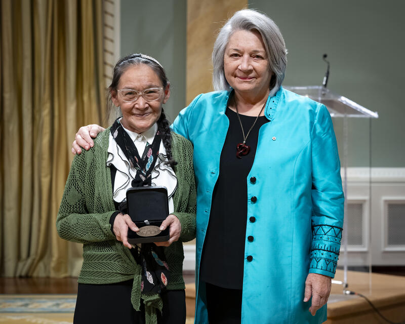 Governor General Mary SImons is posing with a lady who is holding an opened award medal case..