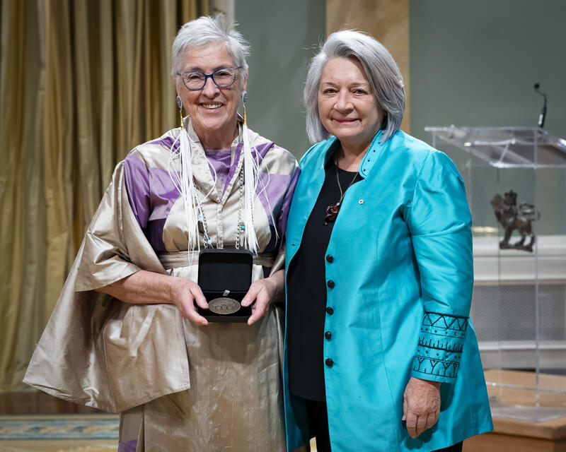 Governor General Mary Simons is posing with a lady who is holding an opened award medal case.