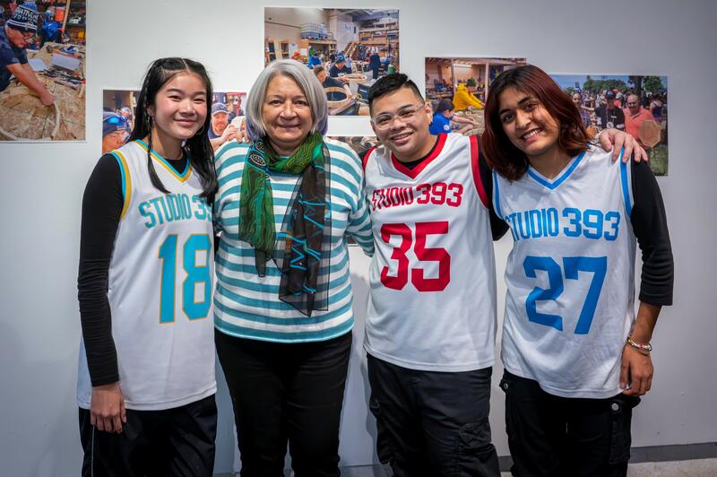 Trois danseurs en tenue de basket-ball sont avec la gouverneure générale Mary Simon, souriant à l'appareil photo.