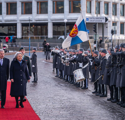 La gouverneure générale Mary Simon et le président Sauli Niinistö marchant sur un tapis rouge. Ils inspectent une garde d’honneur.