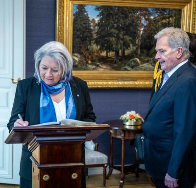 La gouverneure générale Mary Simon signant un livre des visiteurs. Le président Sauli Niinistö est debout à sa droite.