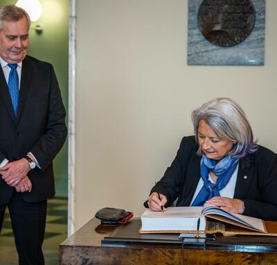 La gouverneure générale Mary Simon signant un livre des visiteurs. Le premier vice-président, Antti Rinne, est debout à sa droite.