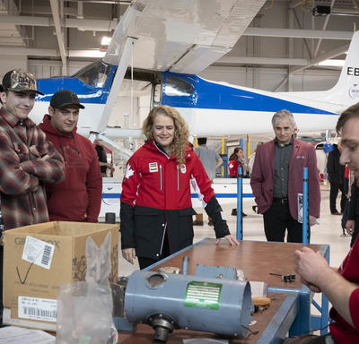 La gouverneure générale dans le hangar du Centre d'excellence en aviation avec des élèves, des enseignants et des avions.