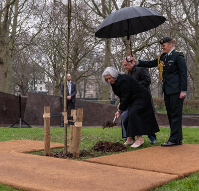 Governor General Mary Simon placing a shovel of dirt at the base of a tree.