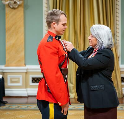 The Governor General is placing a medal on Bravery recipient Constable Daryl Case.