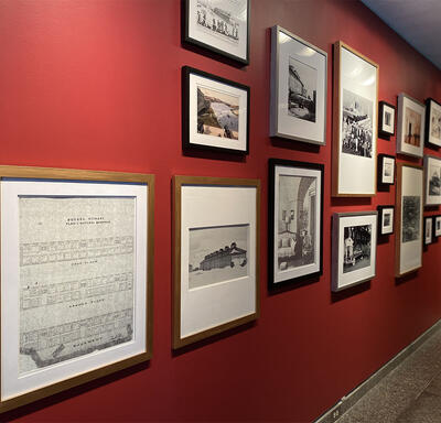 Vue en angle à gauche d'un mur rouge qui présente un mélange de 17 photographies, croquis et peintures sur un mur rouge.
