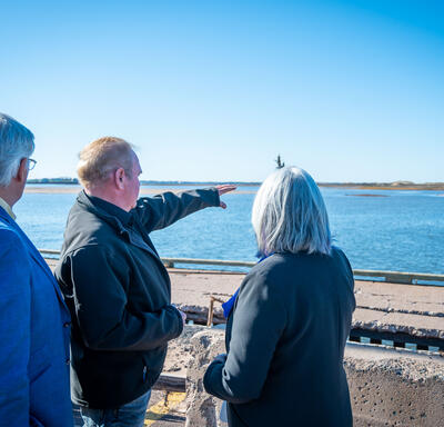 La gouverneure générale parle à quelqu'un en regardant l'eau. Un homme montre quelque chose du doigt.