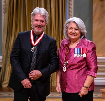 La gouverneure générale Simon se tient à côté d’un homme qui porte une médaille autour du cou.
