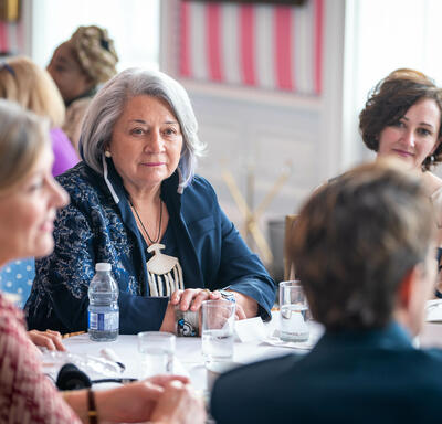 Un groupe de femmes, assises à une table ronde, discutent avec la gouverneure générale Mary Simon, dans la salle de la tente, à Rideau Hall.