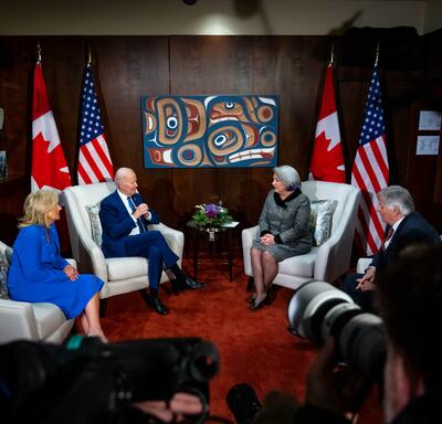La gouverneure générale Simon, M. Whit Fraser, le président Joe Biden et la première dame Jill Biden sont assis dans des fauteuils gris, face à face. Deux drapeaux canadiens et deux drapeaux américains sont derrière eux.