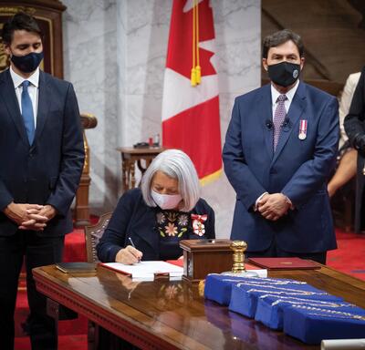La gouverneure générale Mary Simon, assise à une table, signe un document papier.