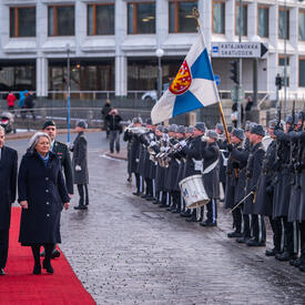La gouverneure générale Mary Simon et le président Sauli Niinistö marchant sur un tapis rouge. Ils inspectent une garde d’honneur.