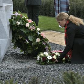 La gouverneure générale du Canada dépose une couronne de fleurs sur une tombe dans un cimetière.