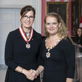 La gouverneure générale, Julie Payette, se tient debout aux côtés de Sophie D'Amours.  Tous deux portent l'insigne de l'Ordre du Canada.