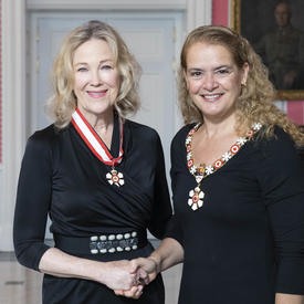 La gouverneure générale, Julie Payette, se tient debout aux côtés de Catherine O'Hara.  Tous deux portent l'insigne de l'Ordre du Canada.
