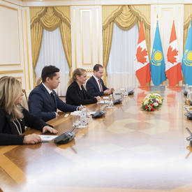 Un groupe de 8 personnes est assis autour d'une grande table oblongue.  La gouverneure générale Julie Payette et Nursultan Nazarbayev, Président du Kazakhstan, sont assis au milieu. À l'arrière-plan se trouvent des drapeaux.