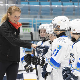 La gouverneure générale Julie Payette serre la main d'enfants habillés en tenue de hockey.  Ils sont sur la glace dans un aréna.