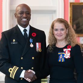Le gouverneur général se tient à côté du lieutenant-commandant Paul Anthony Smith, qui porte, sur son uniforme naval, la Médaille du service méritoire (division militaire) qu'il vient de recevoir.