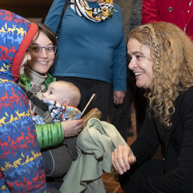 La gouverneure générale, Julie Payette, s'accroupit et parle à un enfant portant un manteau d'hiver.
